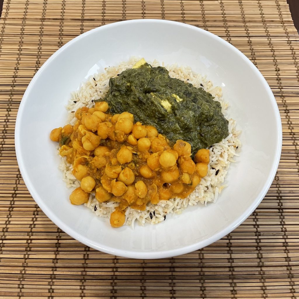 Plate of Indian chana masala (chickpea stew) and Saag paneer (fresh cheese in aromatic spinach sauce) on Rice