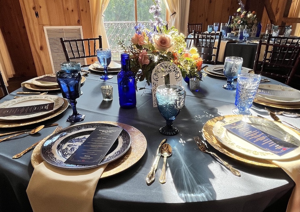 Blue table linen and glassware and gold & white place-settings